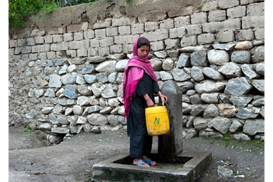 An Afghani girl pumps water into a pail