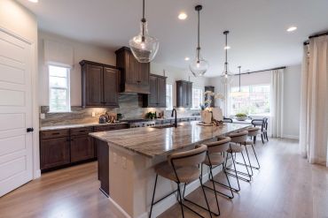 Modern kitchen with a large marble island and pendant lights.