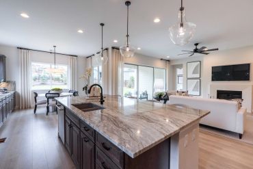 Modern open-concept kitchen and living area with marble island and natural light.