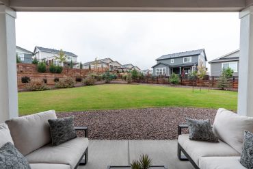 View of a suburban backyard with patio seating and green lawn.