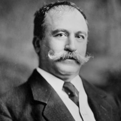 Black and white portrait of a man with a prominent mustache in formal attire.