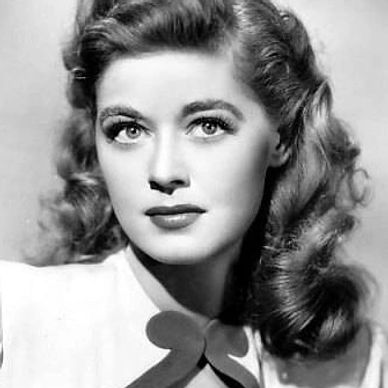 Black and white portrait of a woman with wavy hair and a bow on her blouse.