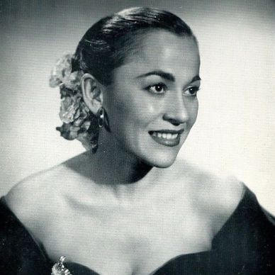Black and white portrait of a smiling woman with flowers in her hair.