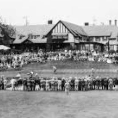 Historic black and white photo of a golf tournament with spectators around the green.