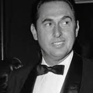 Man in tuxedo looking sideways with a slight smile in black and white photo.