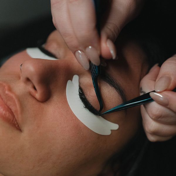 Applying eyelash extensions on a woman's closed eye with precision.
