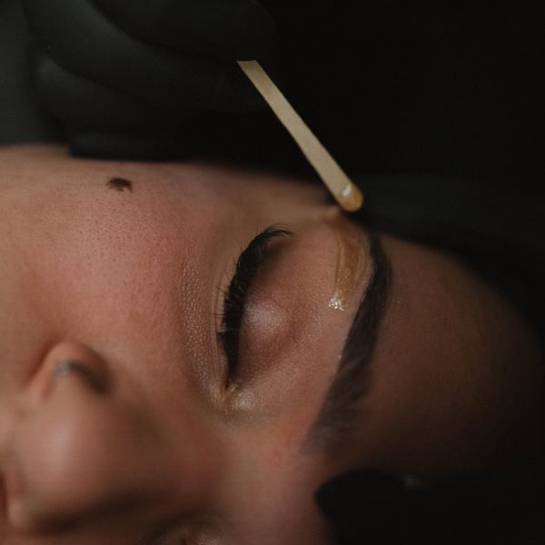 Close-up of a woman having eyebrow tint applied.