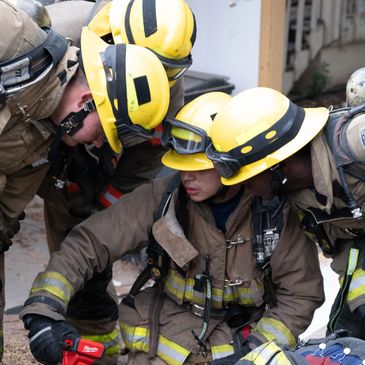 Firefighters in yellow helmets working together during an emergency.