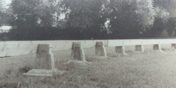 Old black-and-white photo of a row of empty stone seats in an outdoor area.