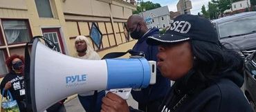 Woman speaking through a megaphone during an outdoor gathering.