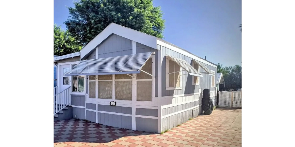 Beige house with a spacious front carport on a sunny day.

