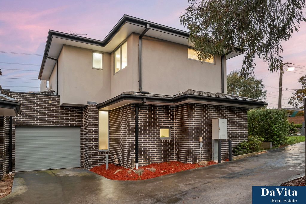 Modern two-story house with brick and stucco exterior at dusk.
