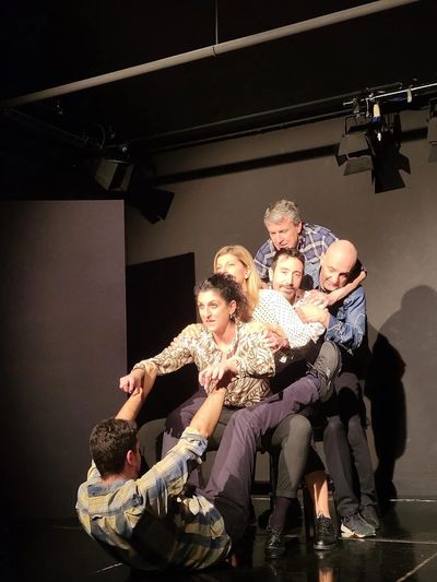 Grupo de personas en escena teatral, interactuando intensamente.