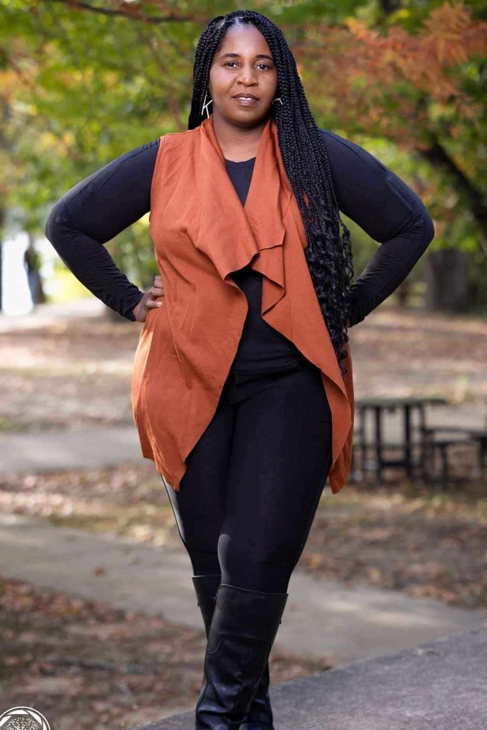 Confident woman stands outdoors with hands on hips.