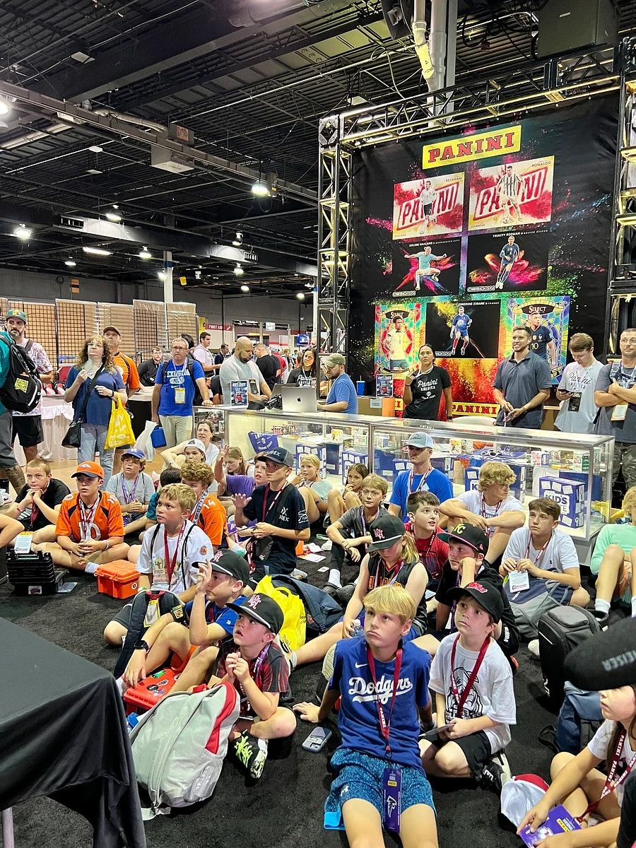 Group of kids at a Panini booth event, sitting attentively on the floor.