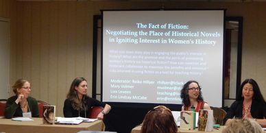 Four women presenters. Projected on a screen behind them is a slide titled "The Fact of Fiction."