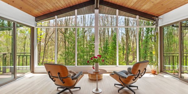Cozy modern seating area with large windows overlooking a lush forest.