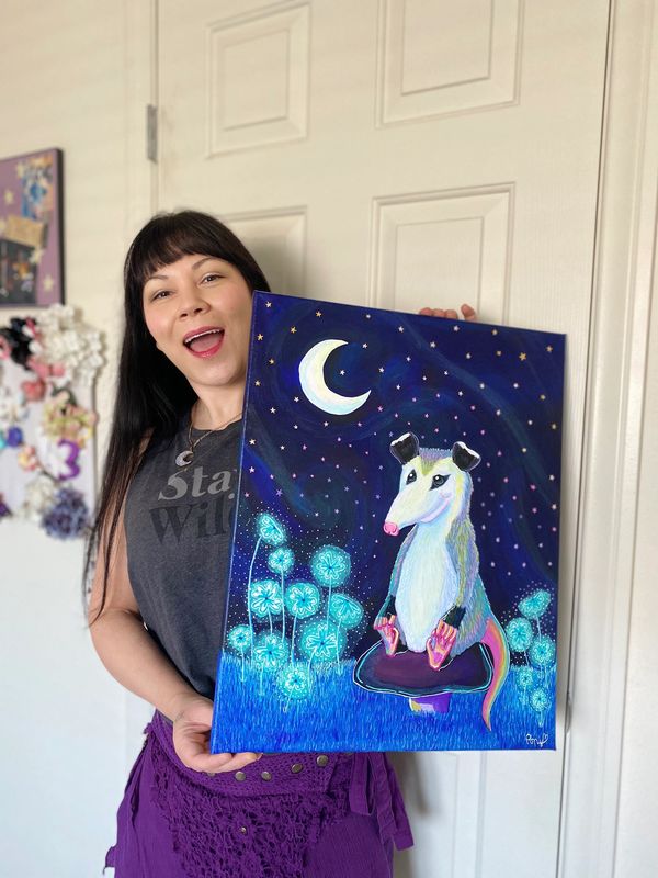 Artist pony Poison poses holding a large acrylic painting of a Cosmic Opossum