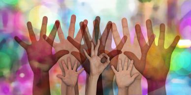 Multiple raised hands with colorful, overlapping shadows on a vibrant background.