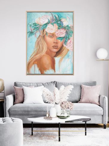 A serene portrait of a woman with a floral crown hangs above a modern gray sofa.