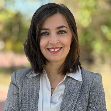 Smiling woman in business attire outdoors.