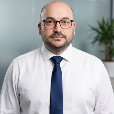 Serious man in glasses and a blue tie.