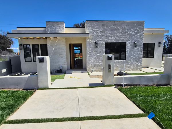 Modern single-story house with stone facade and large windows.