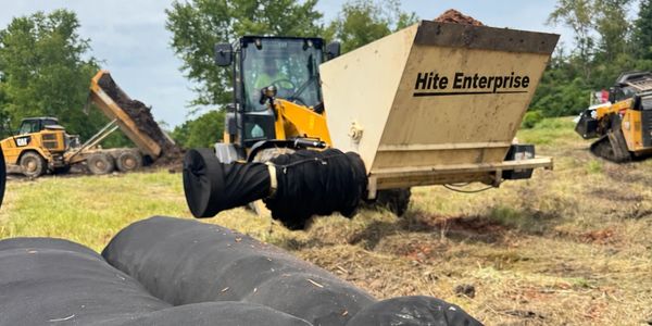 Heavy machinery working on a field with large black tubes.