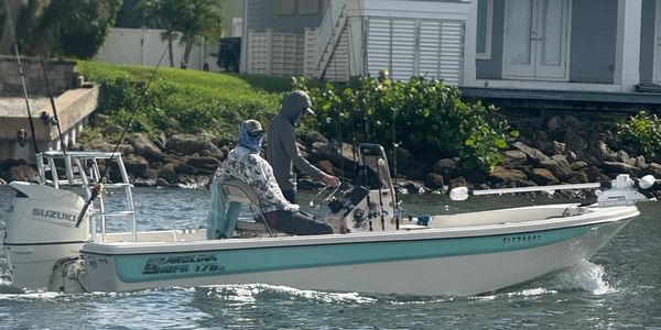 Two people fishing on a small motorboat near the shore.