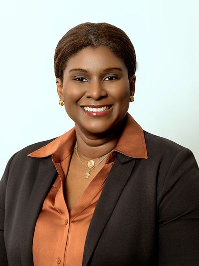 Professional woman smiling, wearing a brown shirt and black blazer.