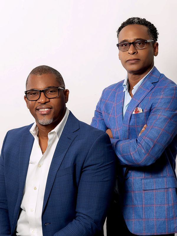Two men in stylish blue suits posing against a white background.