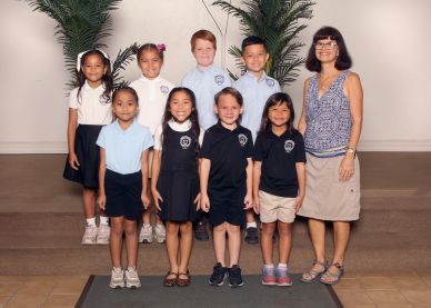 A group of kids and a teacher posing for a picture.
