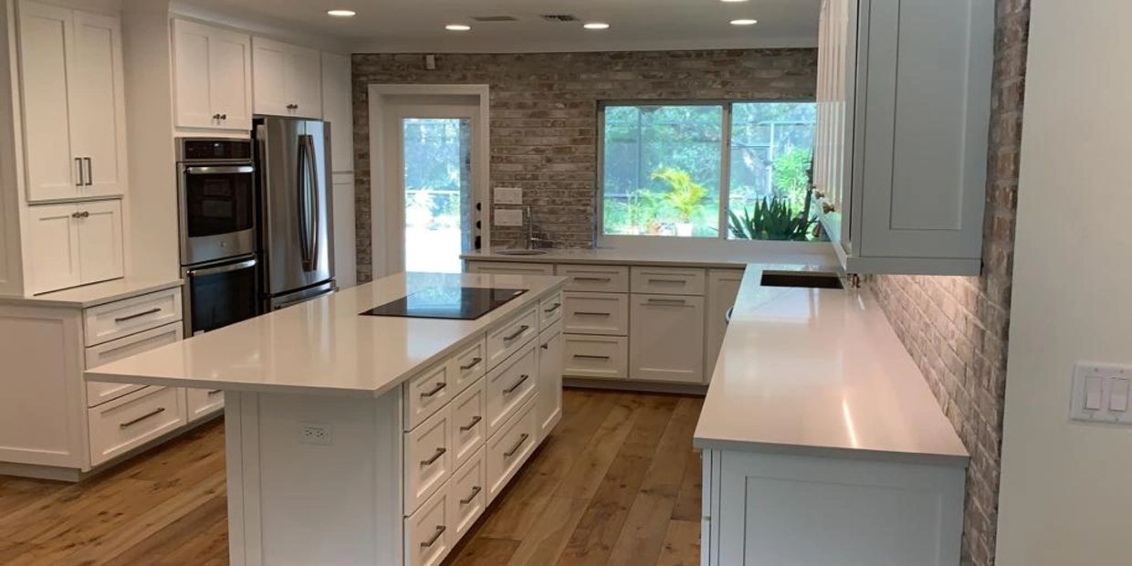 Modern kitchen with white cabinets, brick accent wall, and large central island.
