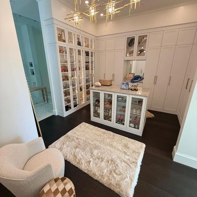 Elegant walk-in closet with white cabinetry and a cozy rug.