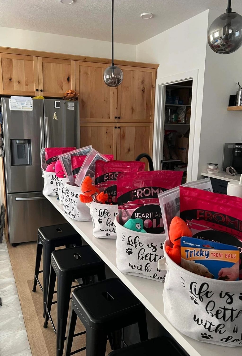 Gift baskets labeled "Life is better with a dog" on a kitchen counter with stools.