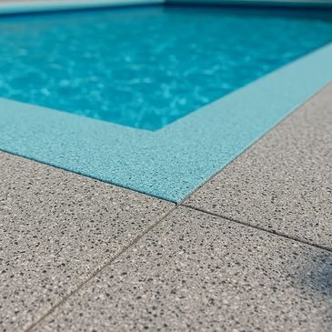 Close-up of pool edge with textured tiles and clear water.