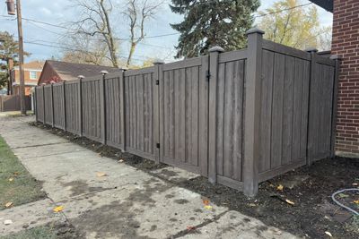 Newly installed tall wooden fence along a sidewalk.