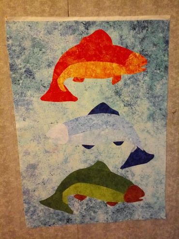 Multicolored fish quilt on a blue spattered background