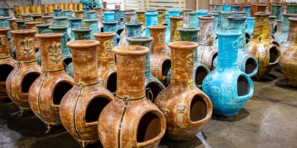 Rows of decorative ceramic chimineas in earthy and blue tones.
