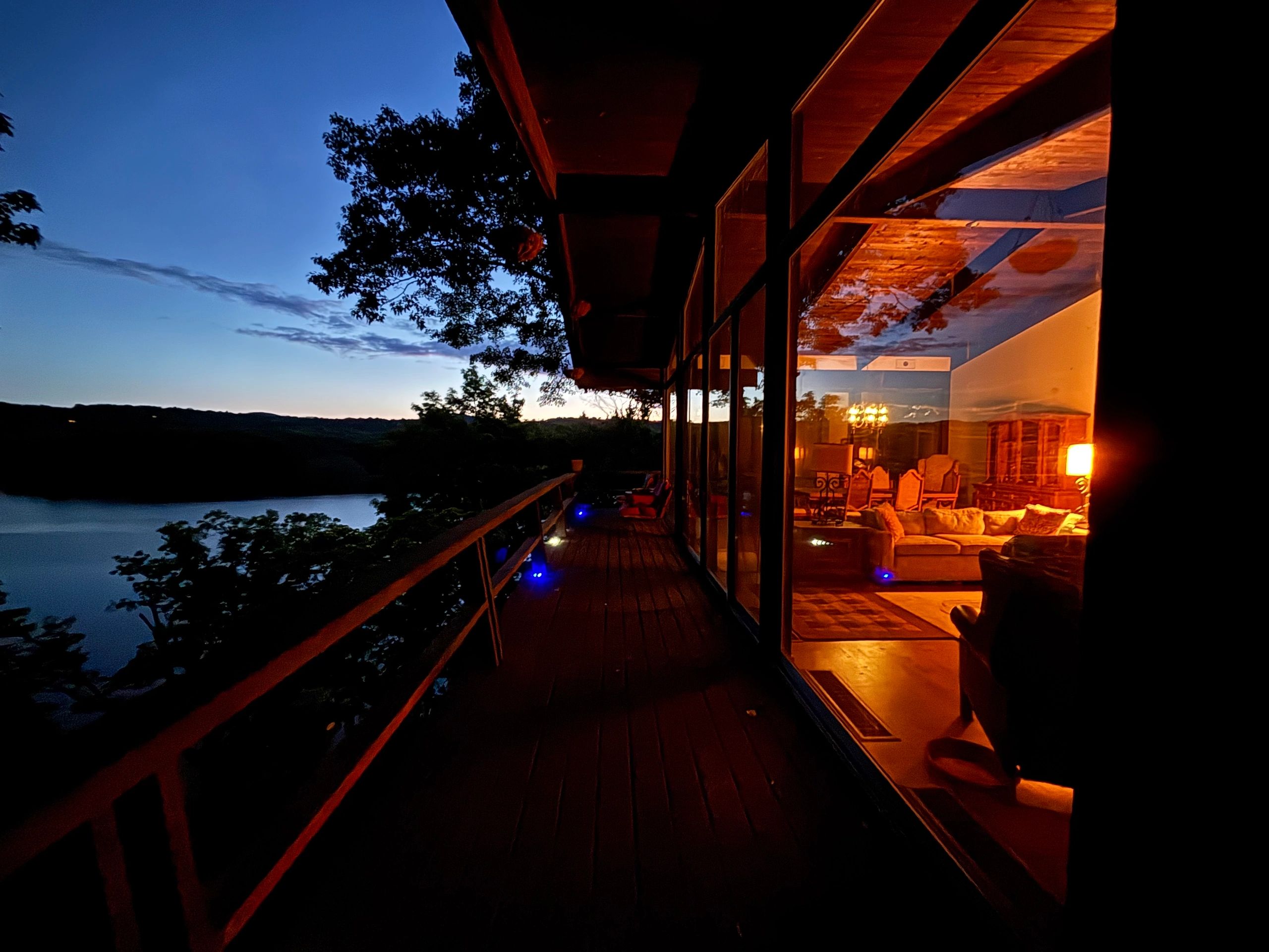 Warmly lit living room reflected on glass at sunset with Candlewood Lake views.