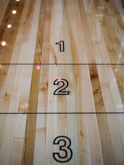 Close-up of a glossy wooden shuffleboard surface with large numbers 1, 2, and 3.