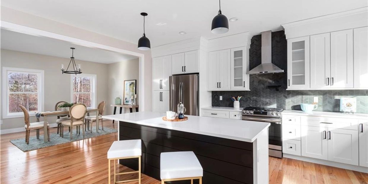 Bright modern kitchen with black and white island and adjacent dining area.