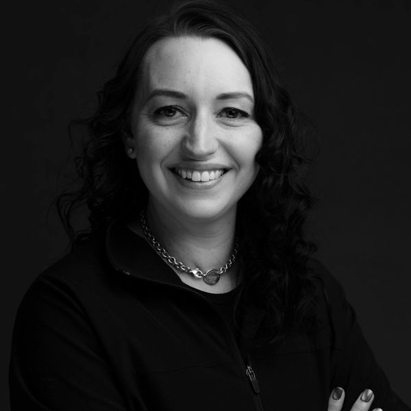 Black and white portrait of a smiling woman with curly hair and a chain necklace.
