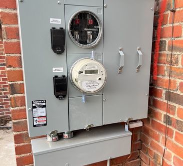 Electrical meter and disconnect box mounted on a brick wall.