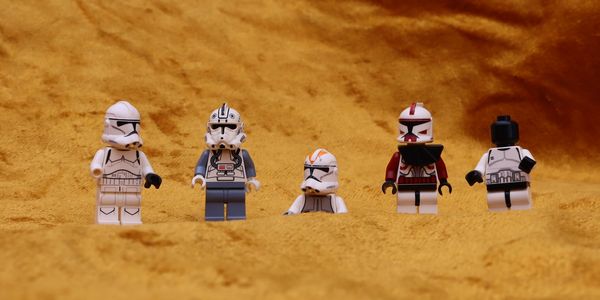 Five Lego Star Wars clone trooper minifigures on a textured orange surface.