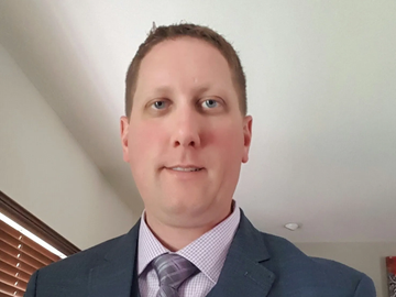 Man in a suit and tie smiling indoors.