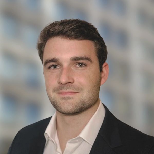 Professional headshot of a young man in business attire.