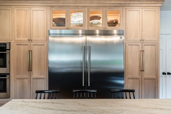 Modern kitchen with stainless steel refrigerator and wooden cabinets.