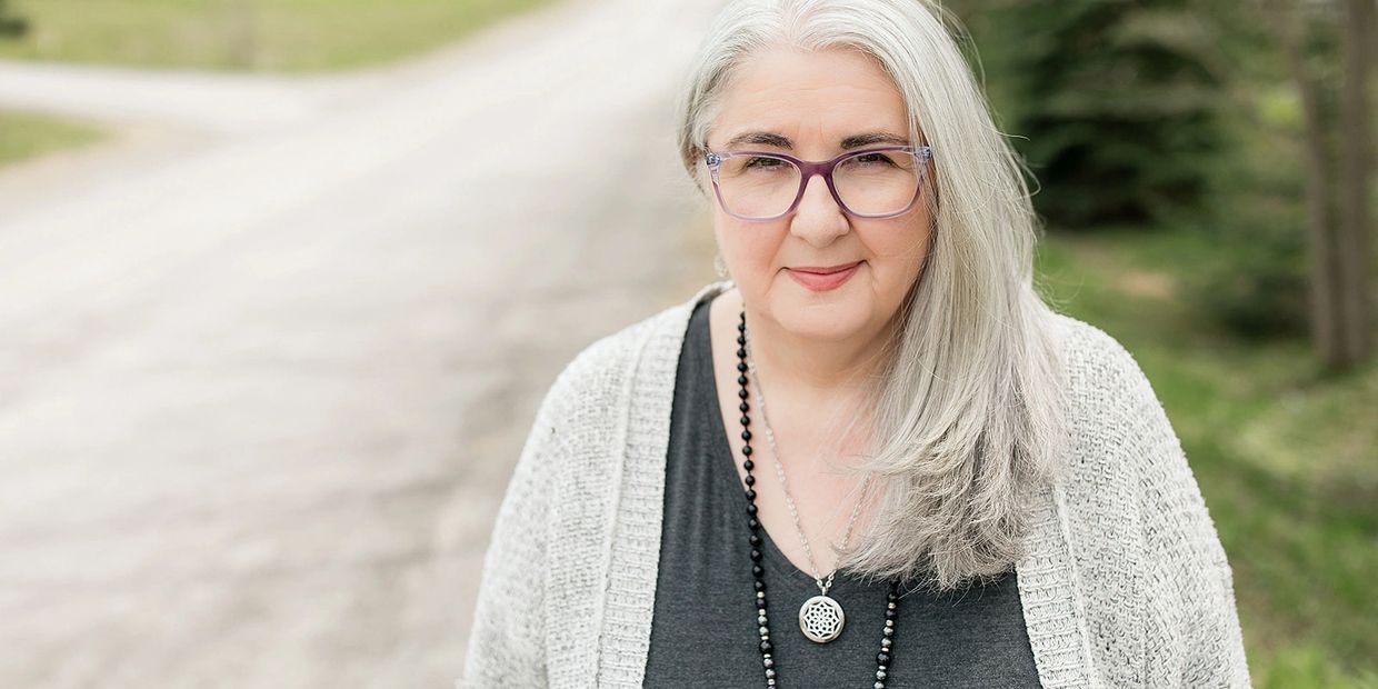 Amanda Wilson, Registered Psychotherapist in a gray sweater with a road and trees in the background