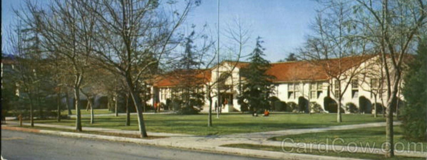 A large building with a red roof surrounded by leafless trees.